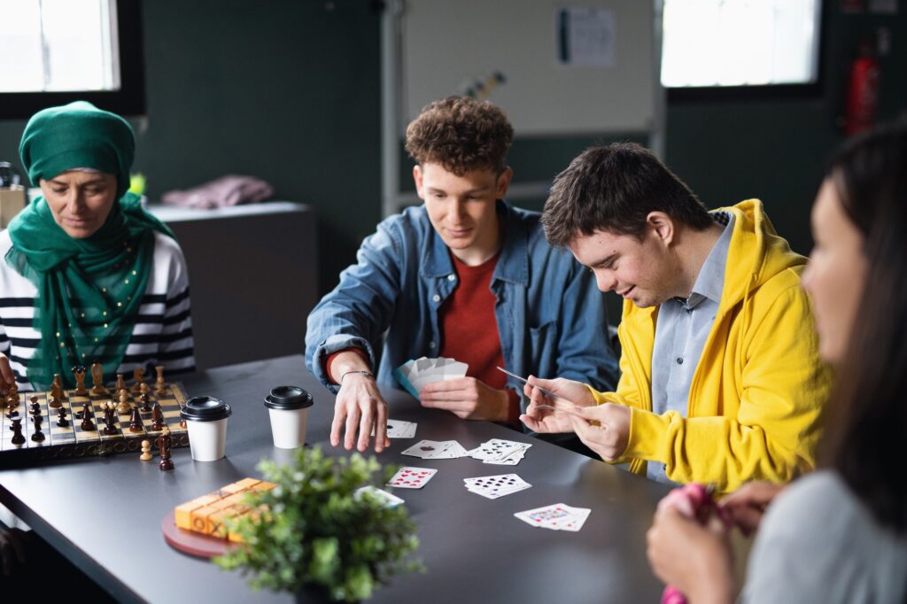 Group of people playing cards and board games in community center, inclusivity of disabled person